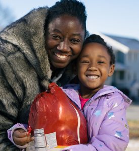 Image of young african american girl holding a frozen turkey.